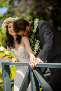 Young groom kissing young hawaiian bride on her shoulder.