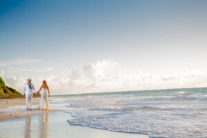 Navy officer walking on the beach with his bride.